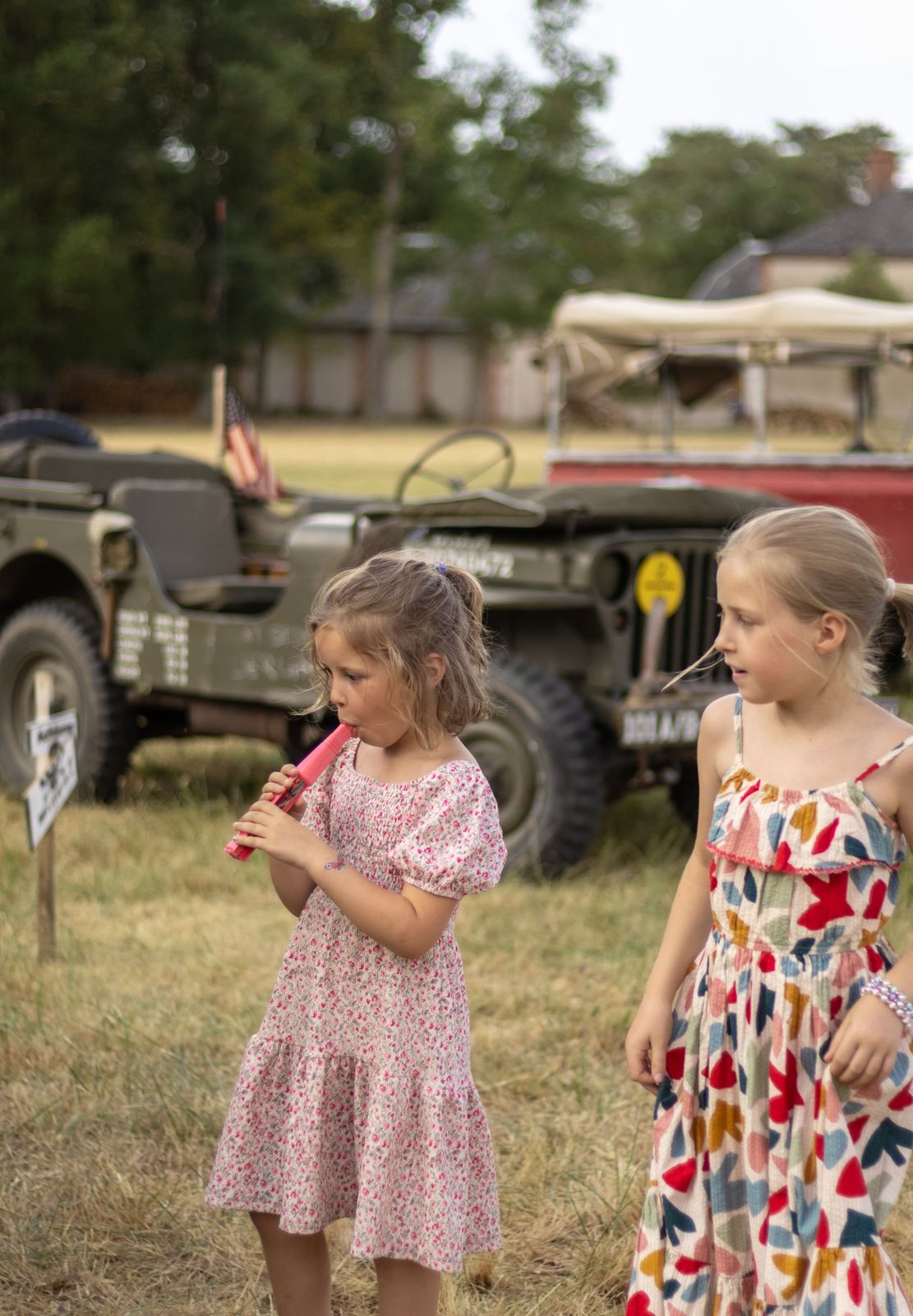 Deux petites filles jouent devant des jeeps d’époque