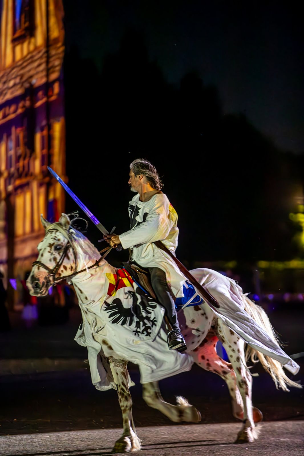Un cavalier en tunique blanche à l’aigle noir, sur un cheval pommelé