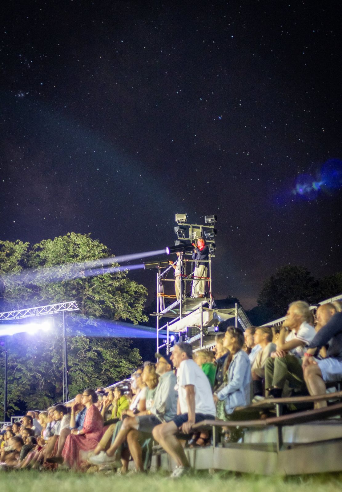 Les spectateurs sous les étoiles, devant les projecteurs sur leur tour