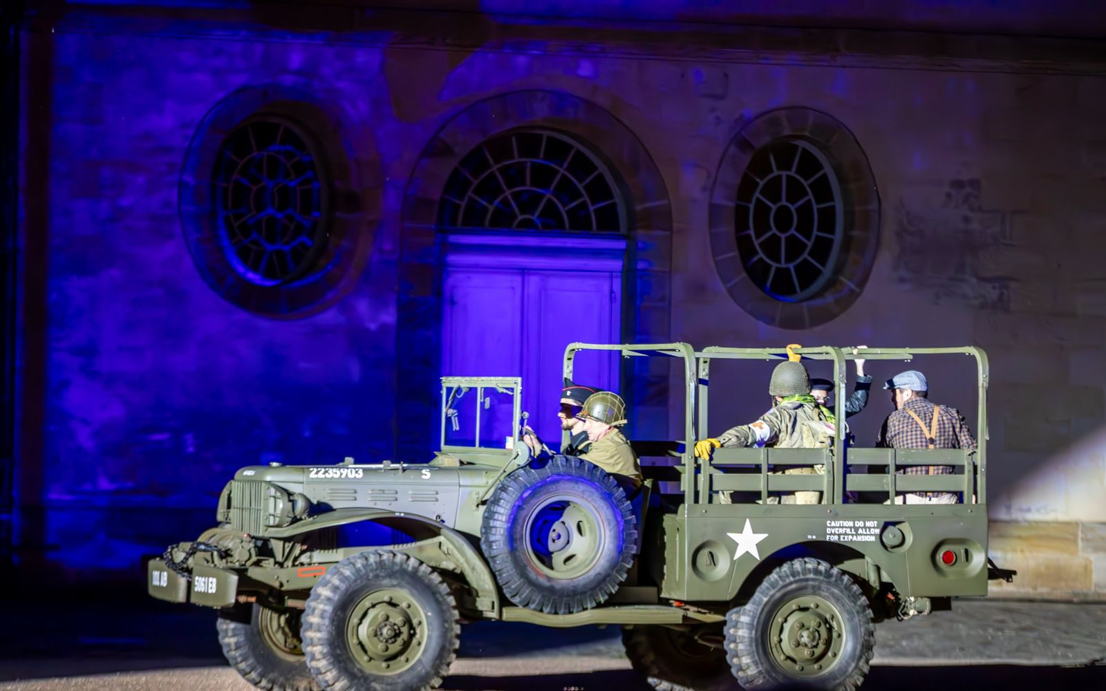 Un camion militaire d’époque devant une façade bleue